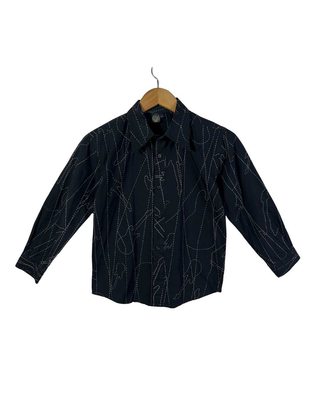 Black shirt with white patterns on a wooden hanger against a white background