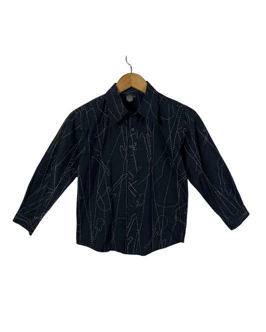 Black shirt with white patterns on a wooden hanger against a white background